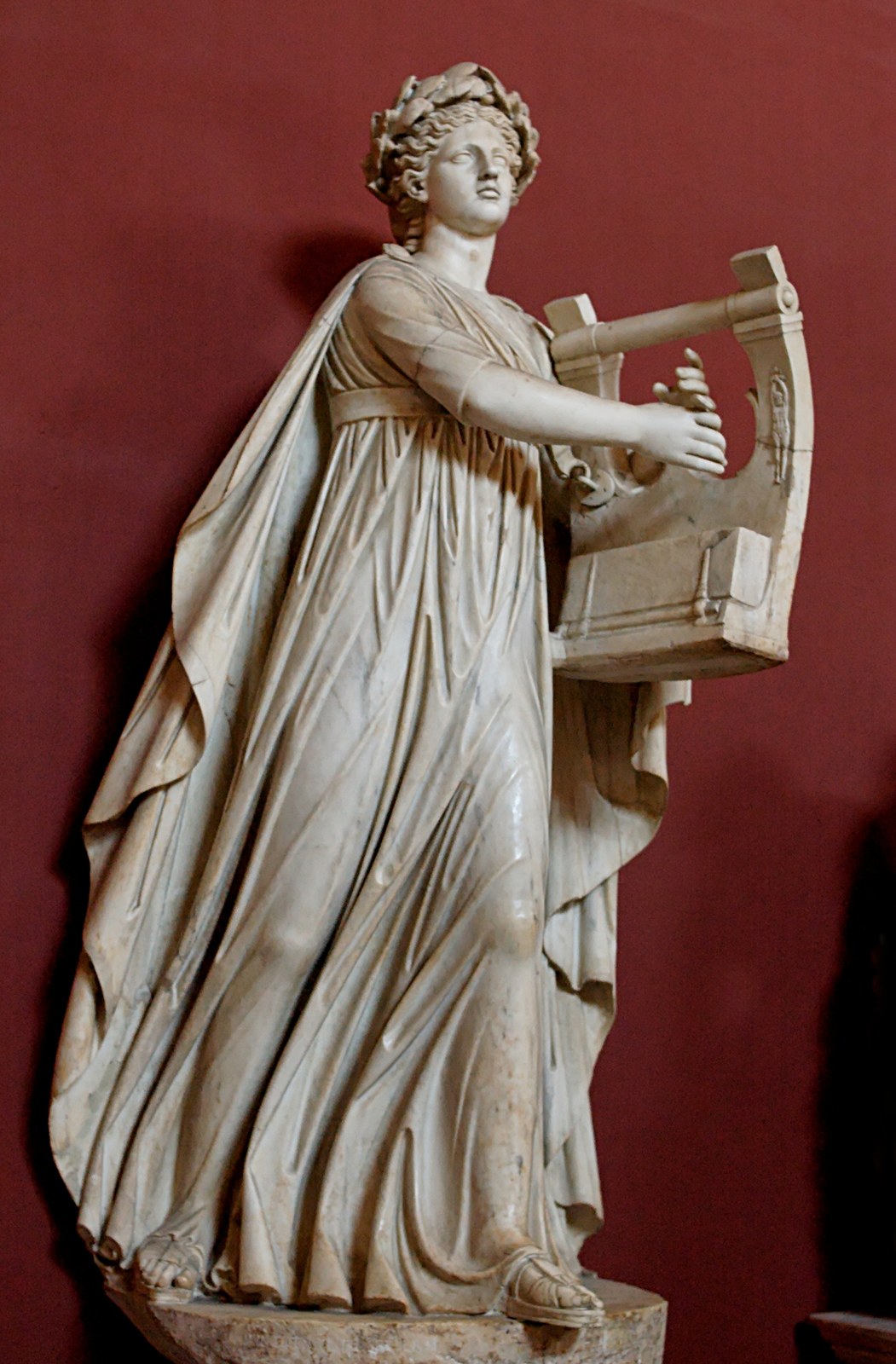 Roman marble statue of Apollo in a long flowing robe, playing a lyre, in the Vatican Museums.